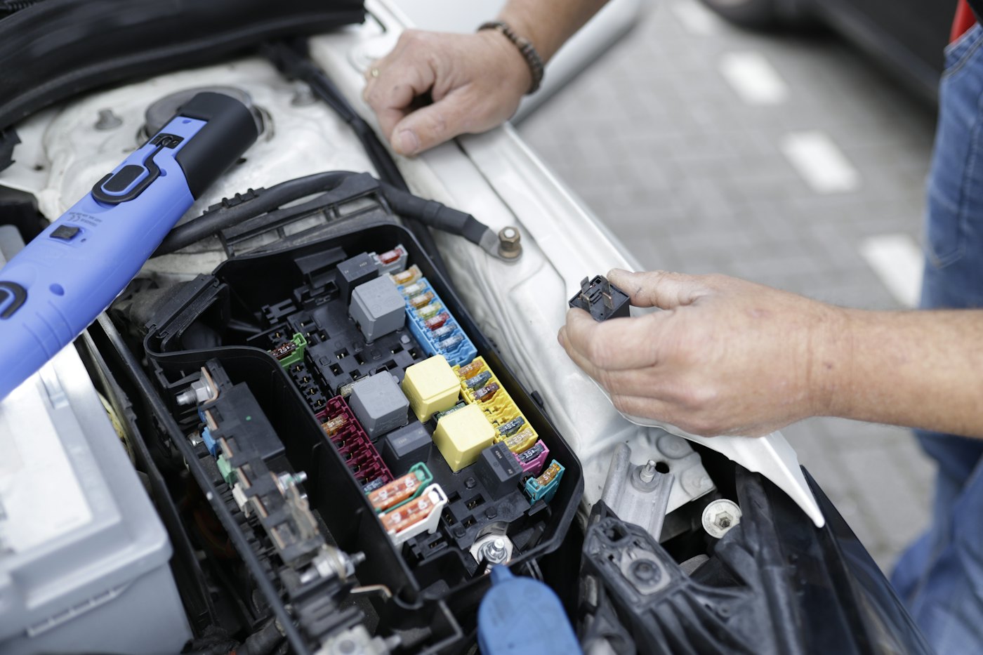 Mechanic testing a car's fuse and relay box